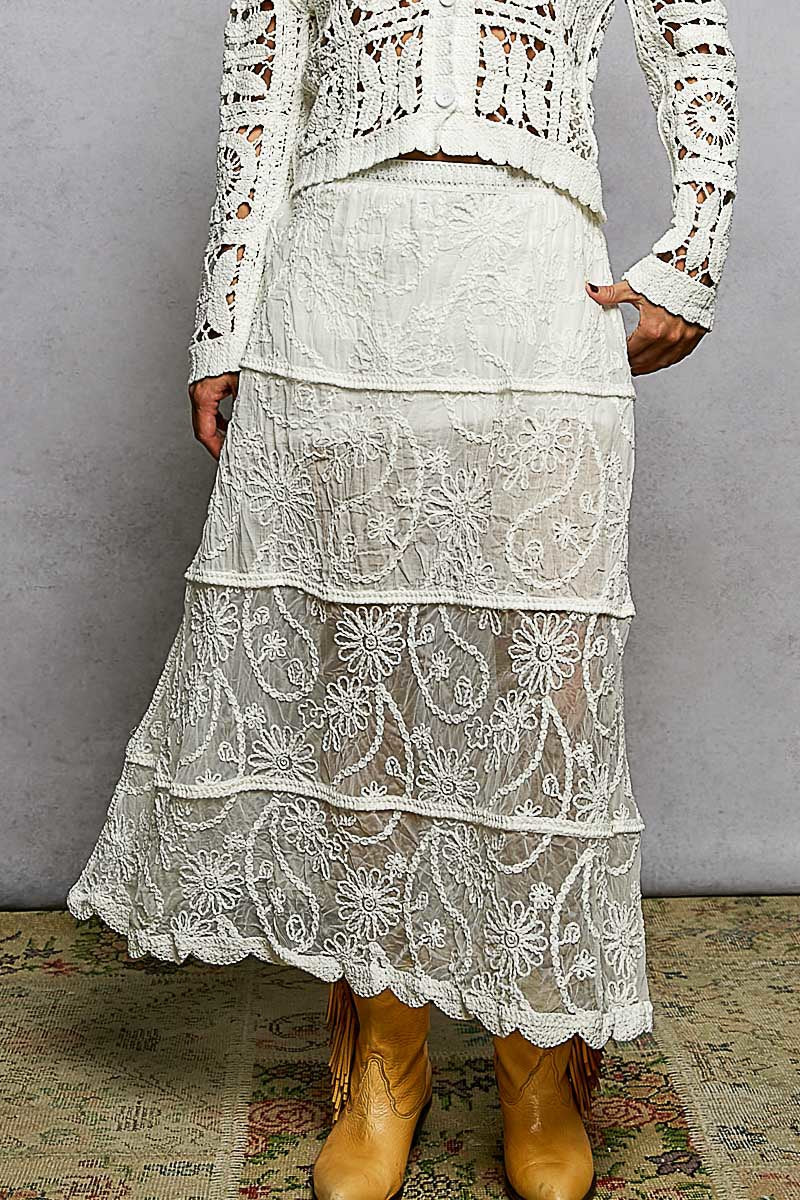 Person wearing a white lace outfit with boots on a textured floor.