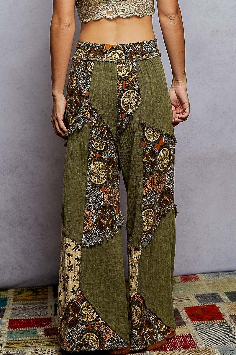 Green pants with intricate patterns worn by a person against a plain background