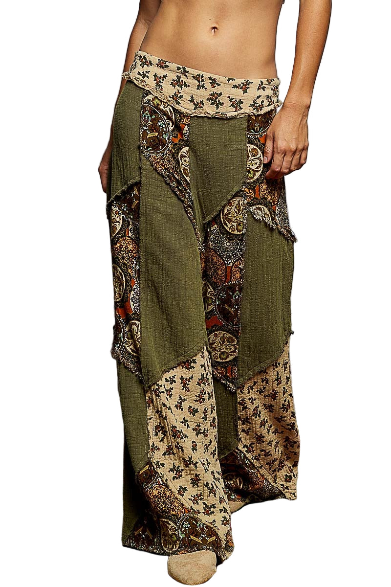 Person wearing a pair of green and patterned wide-leg pants on a colorful rug.