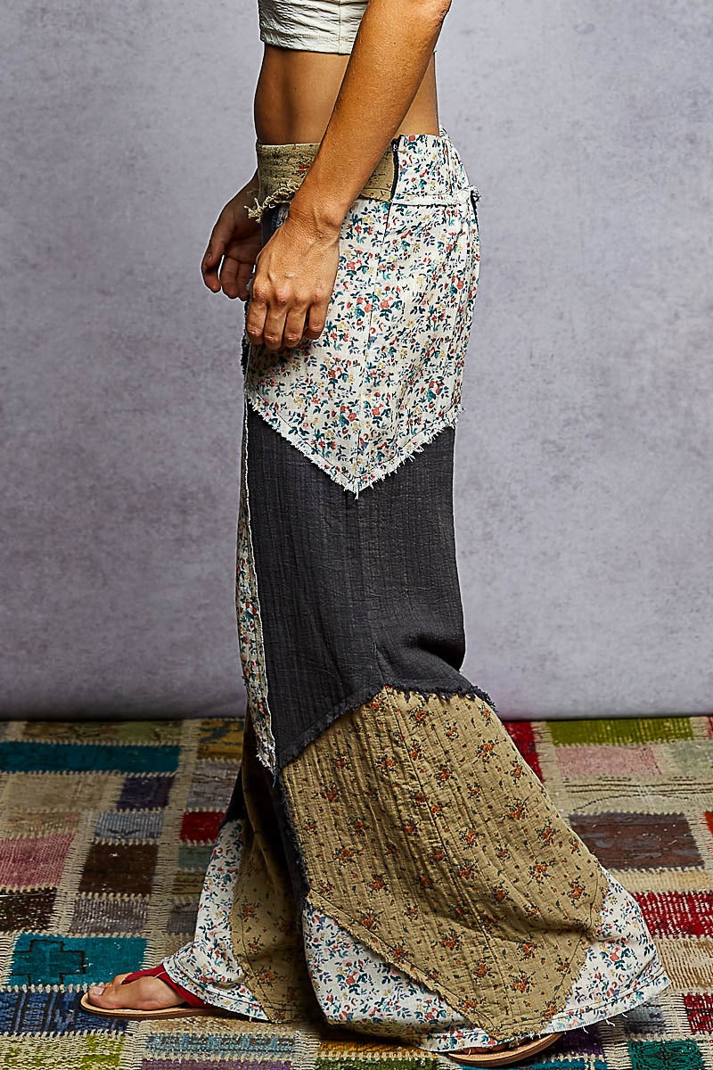 Person wearing a long, patterned skirt with a plain background