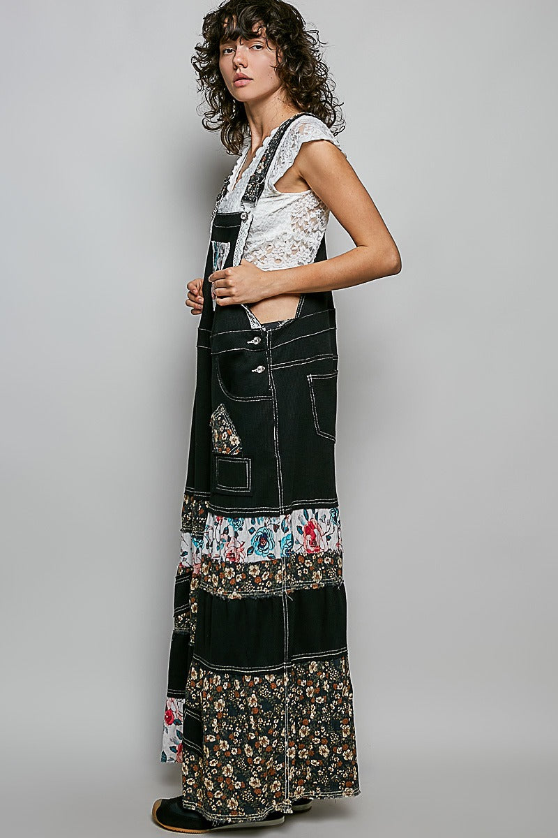 Woman wearing a long, black apron with floral patterns on a gray background