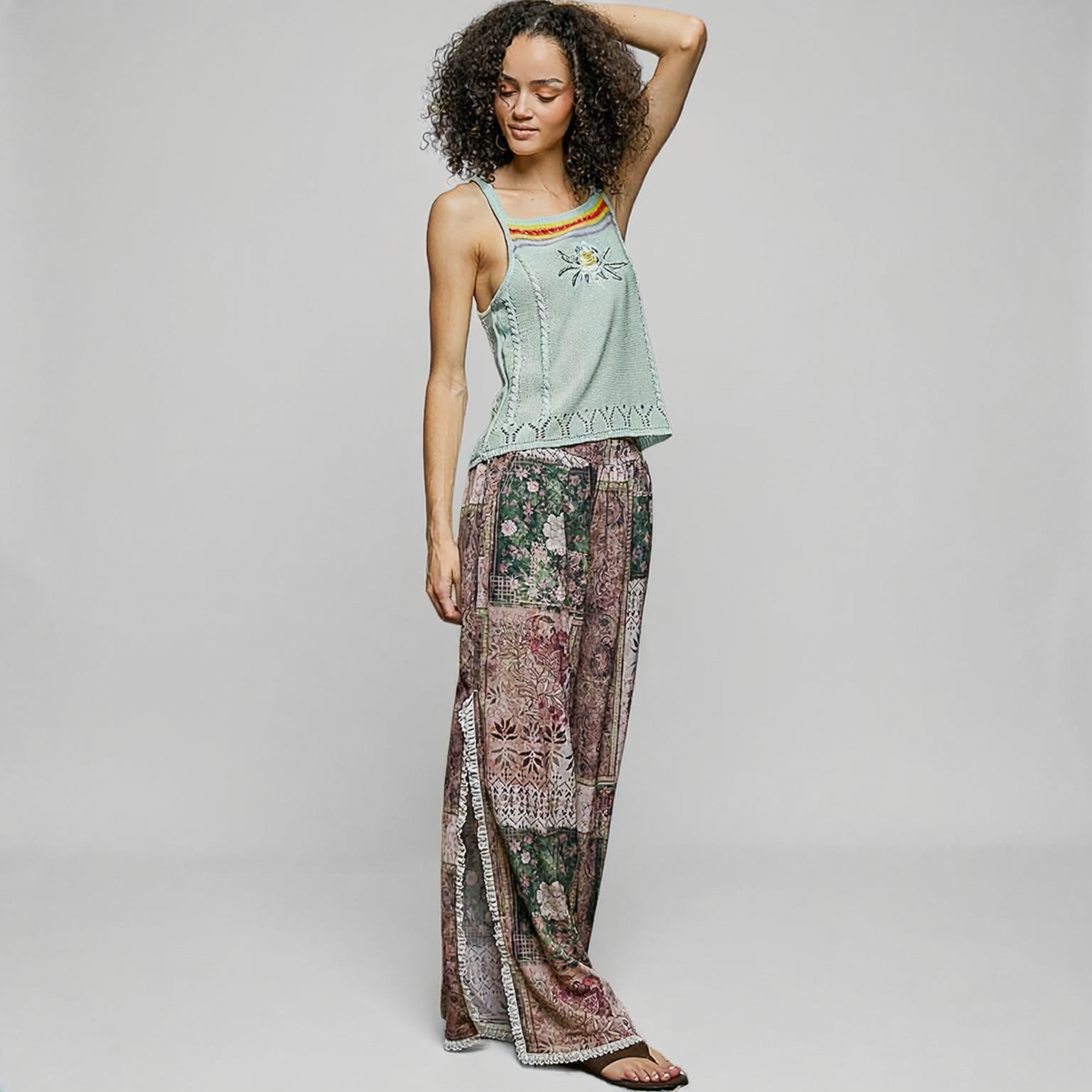 POL Clothing Rose Multi patchwork wide-leg pants on a model, showing floral print and lace-trimmed side openings.
