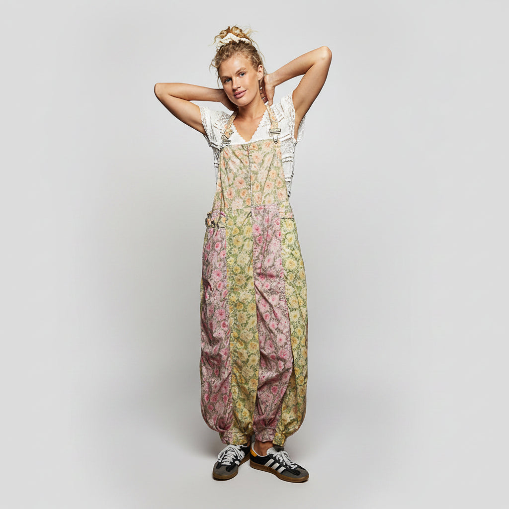 A woman modeling a pair of loose, balloon-style floral overalls with a white short-sleeve top and black sneakers, posed against a solid white background.