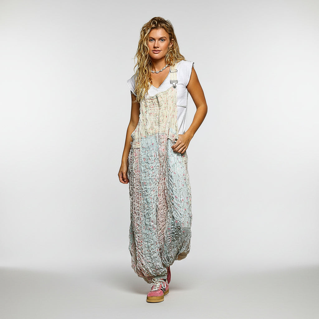 A woman modeling a bohemian-style maxi dress with a white sleeveless top overlay and a textured, patterned skirt in pastel shades of blue, pink, and beige, set against a plain white background.