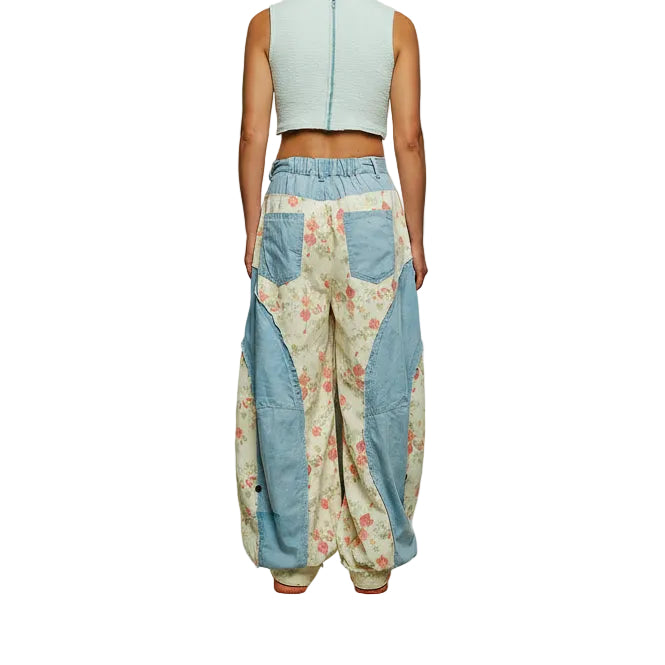Floral patchwork pants with blue accents worn by a person against a gray background