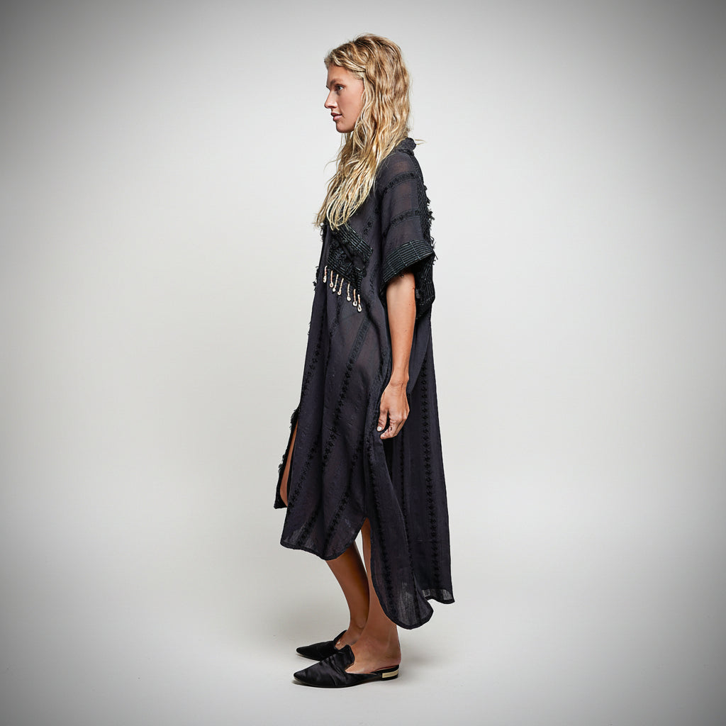 Woman wearing a black poncho with cut-out details on a white background