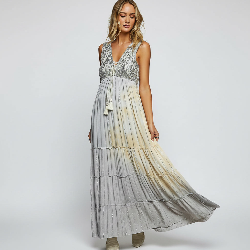 Woman wearing a long, layered dress with a gradient effect against a plain background