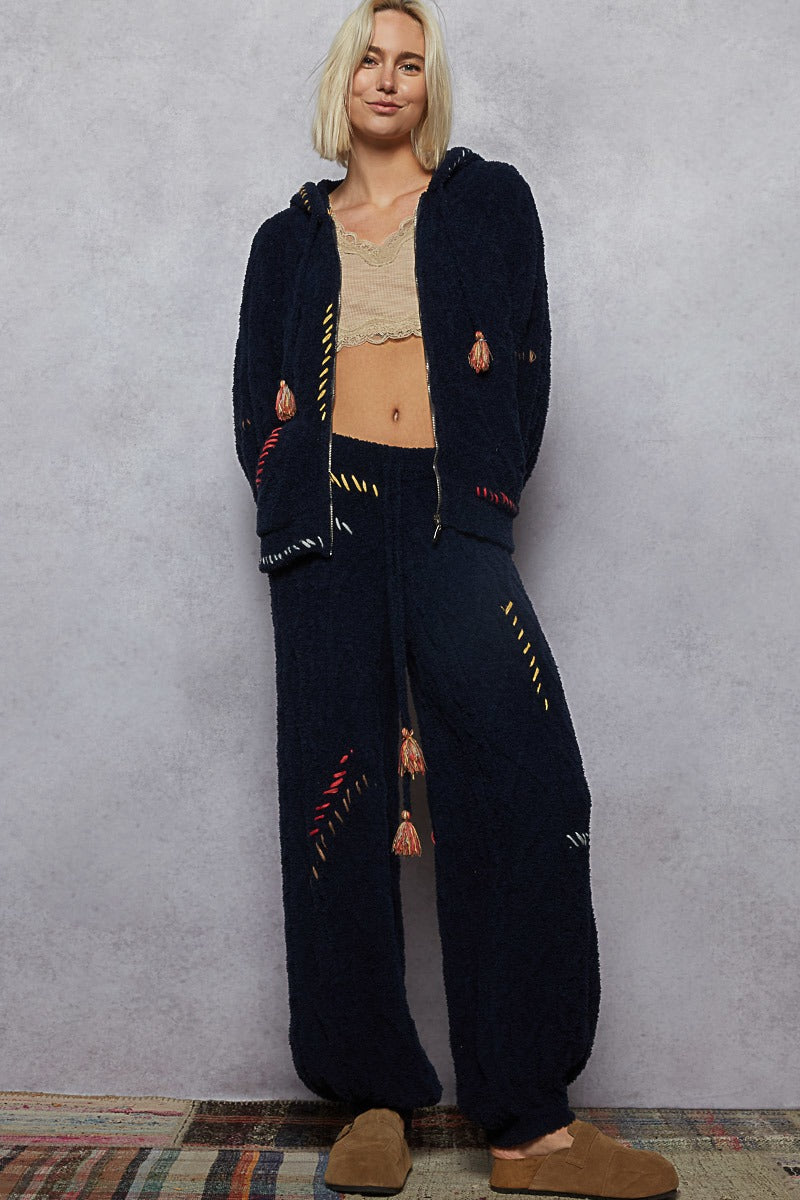 Person wearing a dark blue hoodie and pants with colorful patterns on a gray background