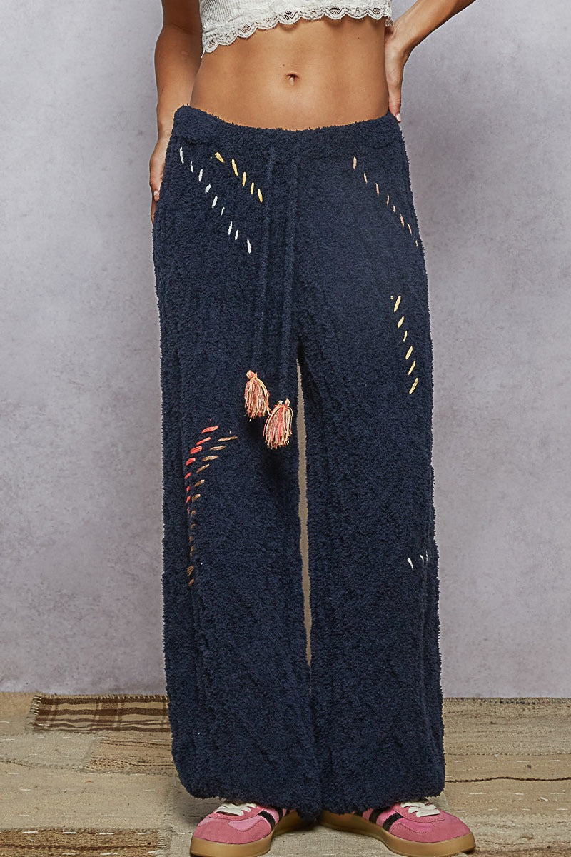 Navy blue embroidered pants worn by a person on a neutral background