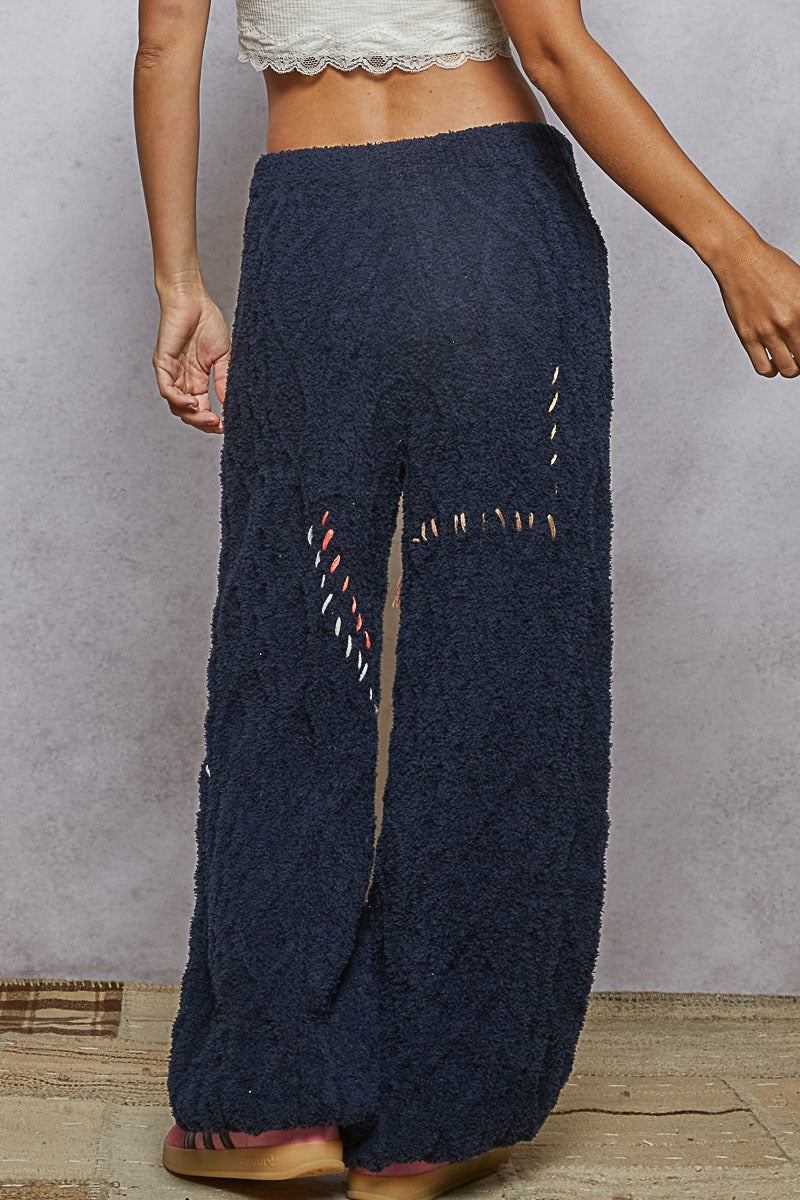 Navy blue textured pants with decorative stitching on a plain background