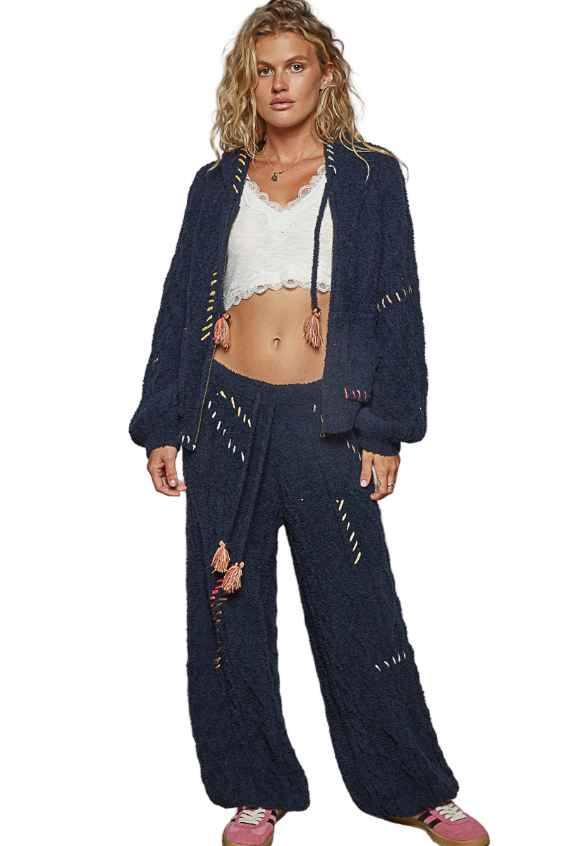 Woman wearing a navy blue knitted cardigan and pants on a white background