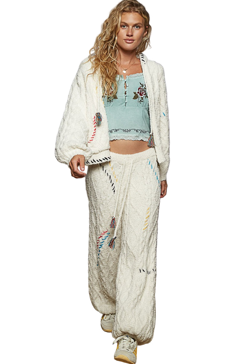 Woman wearing a light blue embroidered top and white dhoti pants on a white background