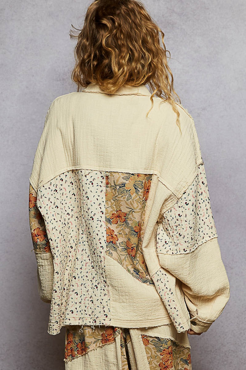 Person wearing a layered outfit with floral and textured patterns against a plain background