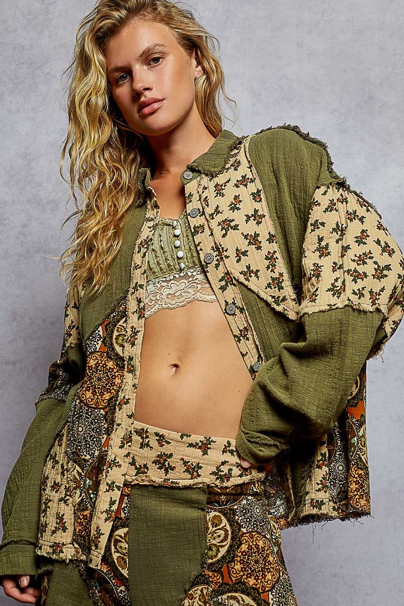 Woman wearing a patterned outfit with a green jacket against a gray background