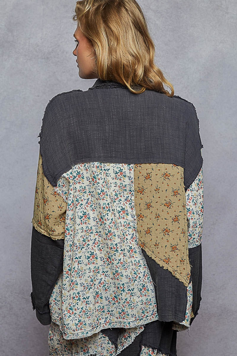 Person wearing a patchwork jacket with floral and beige patterns on a gray background