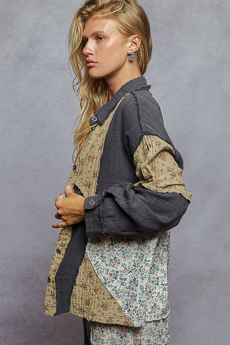 Woman wearing a layered outfit with floral and textured fabrics against a gray background