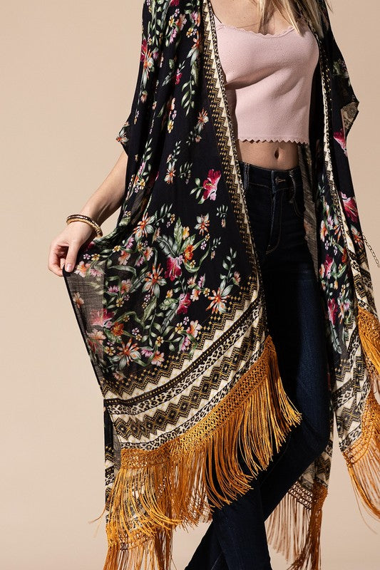 a woman in a pink top is holding a black and yellow shawl