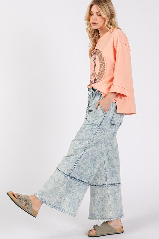 Woman wearing a peach top and light blue jeans on a white background