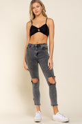 a woman in a black bra top and ripped jeans