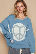 a woman in a blue sweater with a peace sign on it