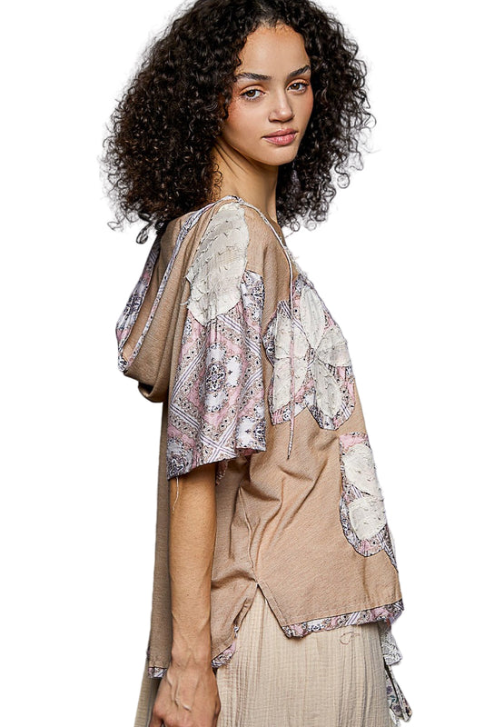 Woman wearing a beige and patterned top with a plain background