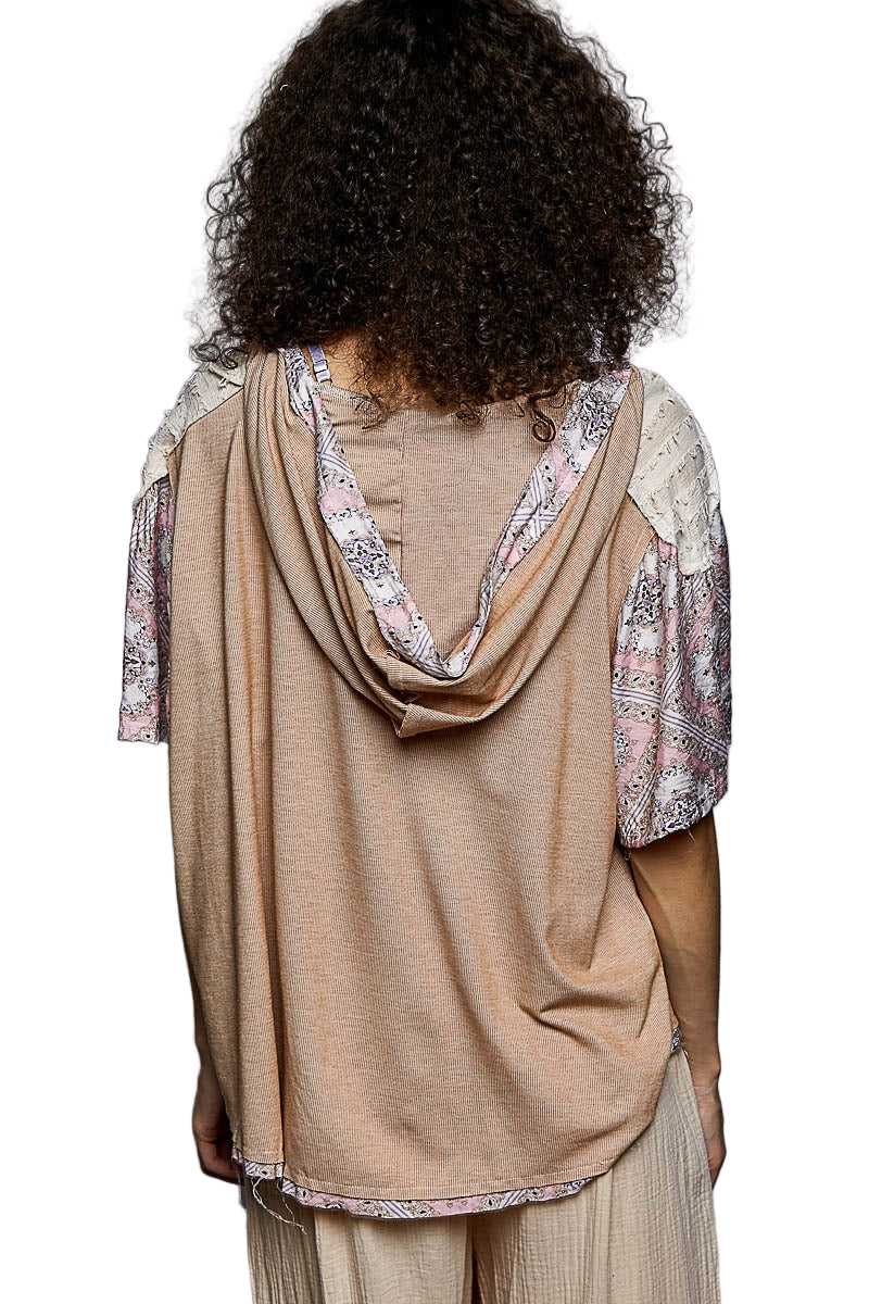 Woman wearing a beige top with floral sleeves and a matching scarf on a white background