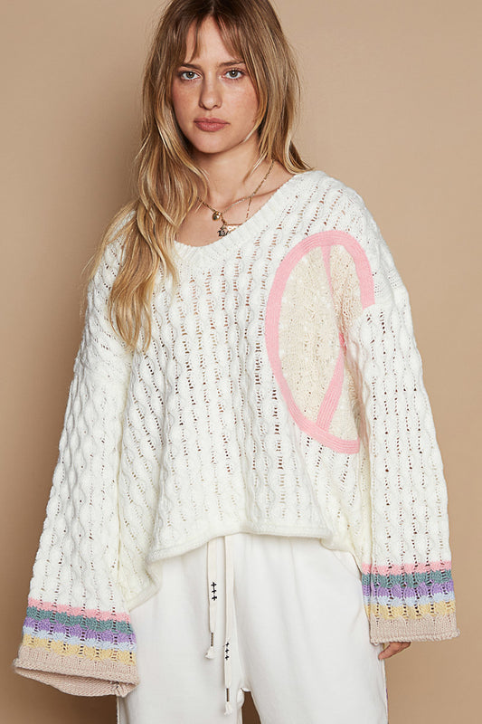 a woman wearing a white sweater with a peace sign on it