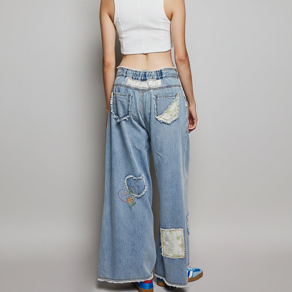 POL Clothing women's light blue wide-leg patchwork denim pants, back view showing lace eyelet waistband and floral patches
