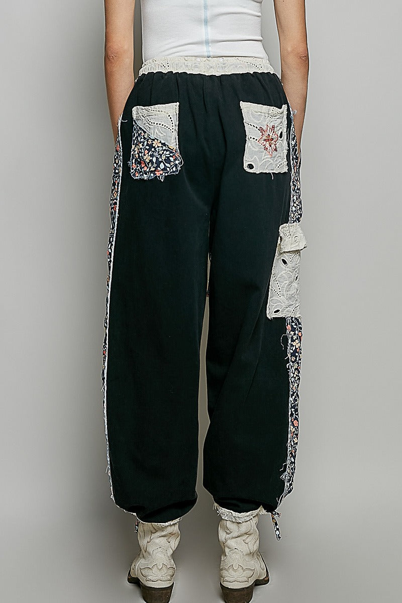 Black patchwork pants with floral patterns on a plain background