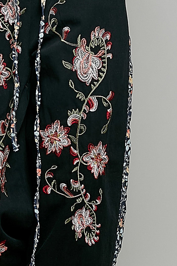 Black garment with intricate floral embroidery on a gray background