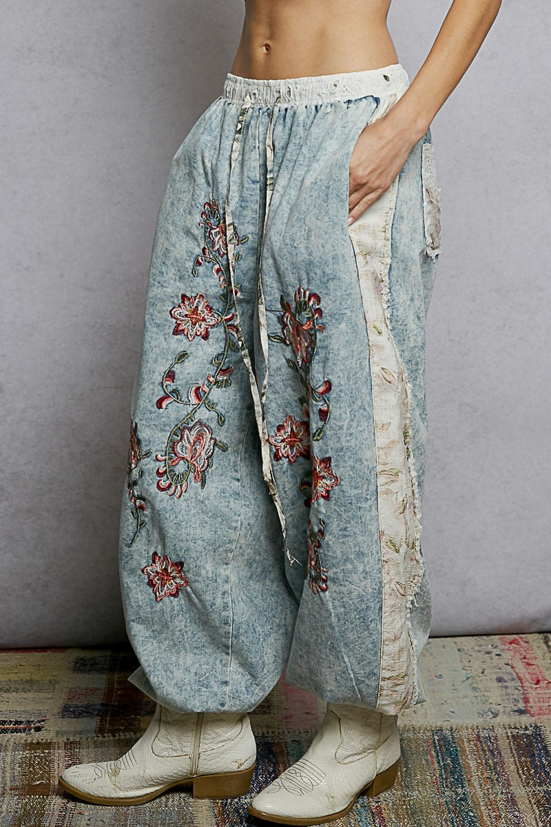 Light blue embroidered pants worn by a person on a gray background