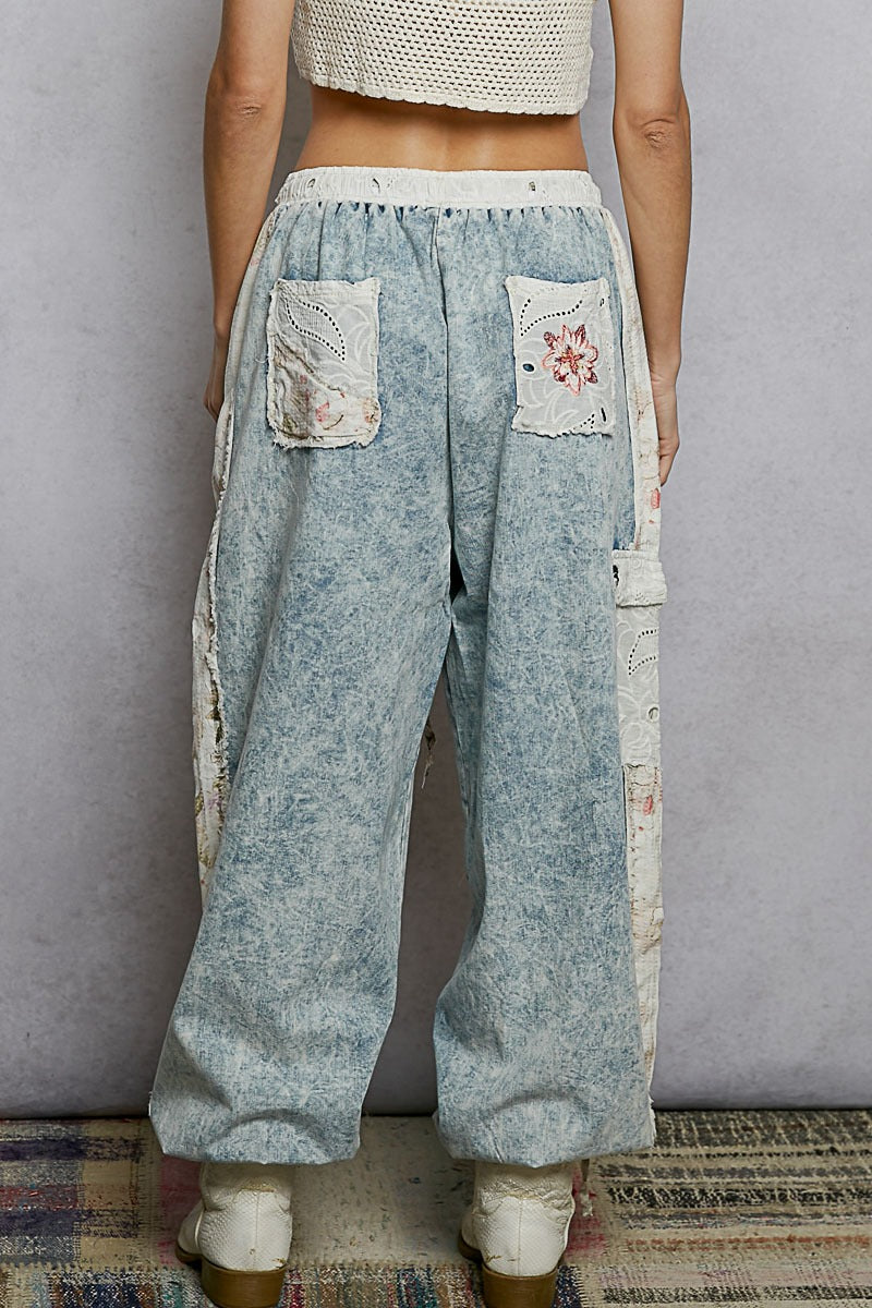 Light blue distressed jeans with floral patches worn by a person against a plain background
