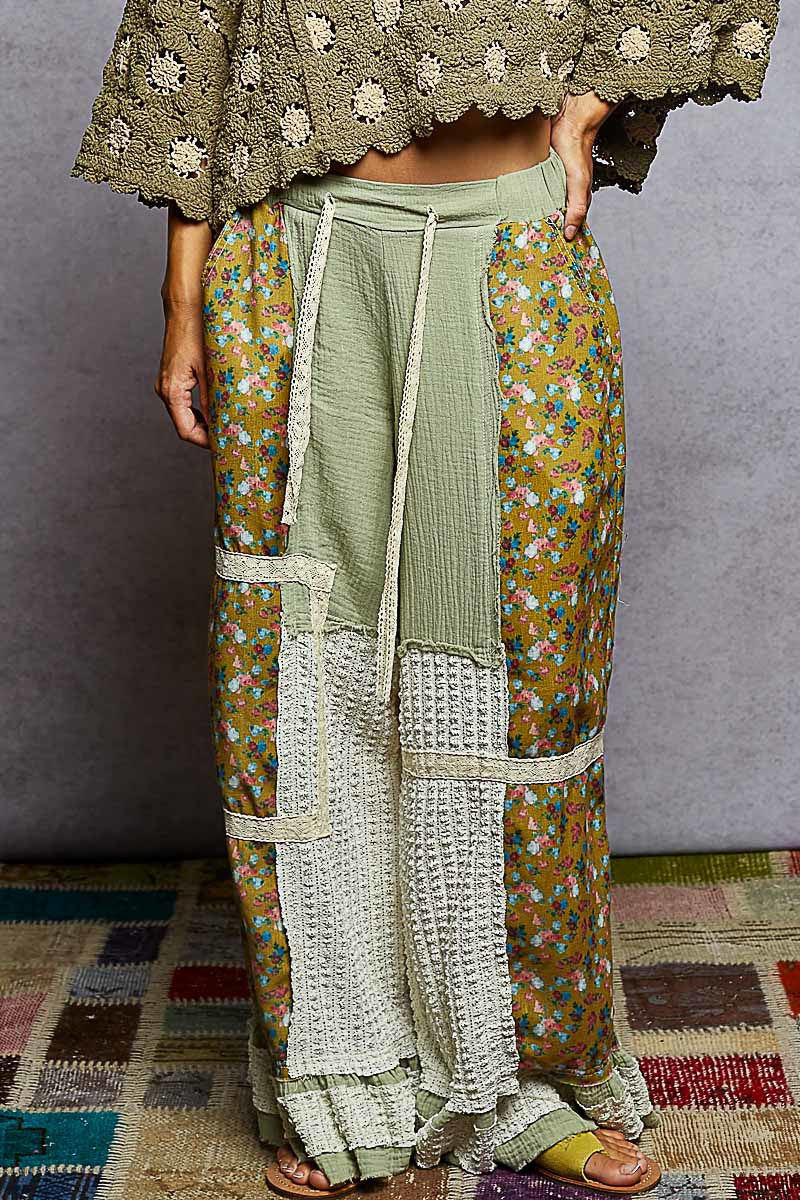 Person wearing a traditional outfit with a floral skirt and green top on a textured floor.