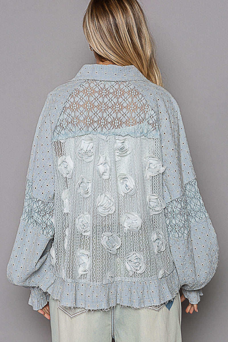 a woman wearing a blue blouse with white flowers on it