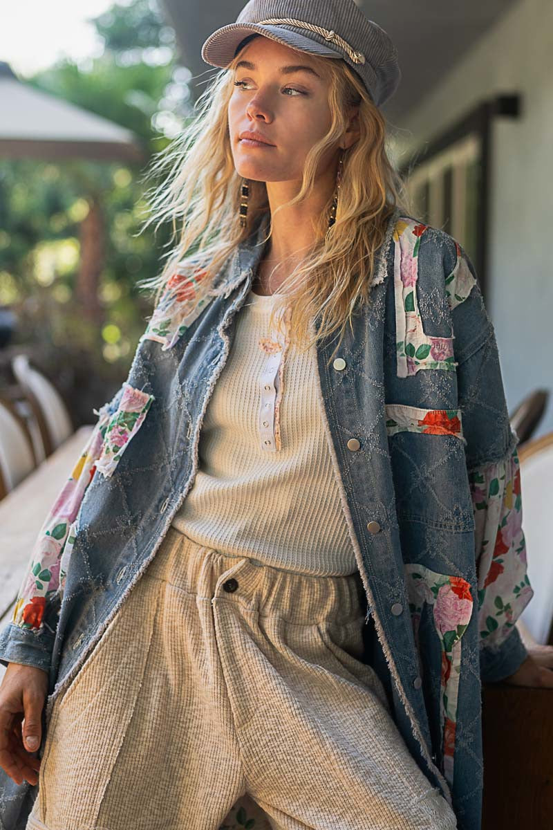 Woman wearing a floral jacket over a sweater and pants outdoors