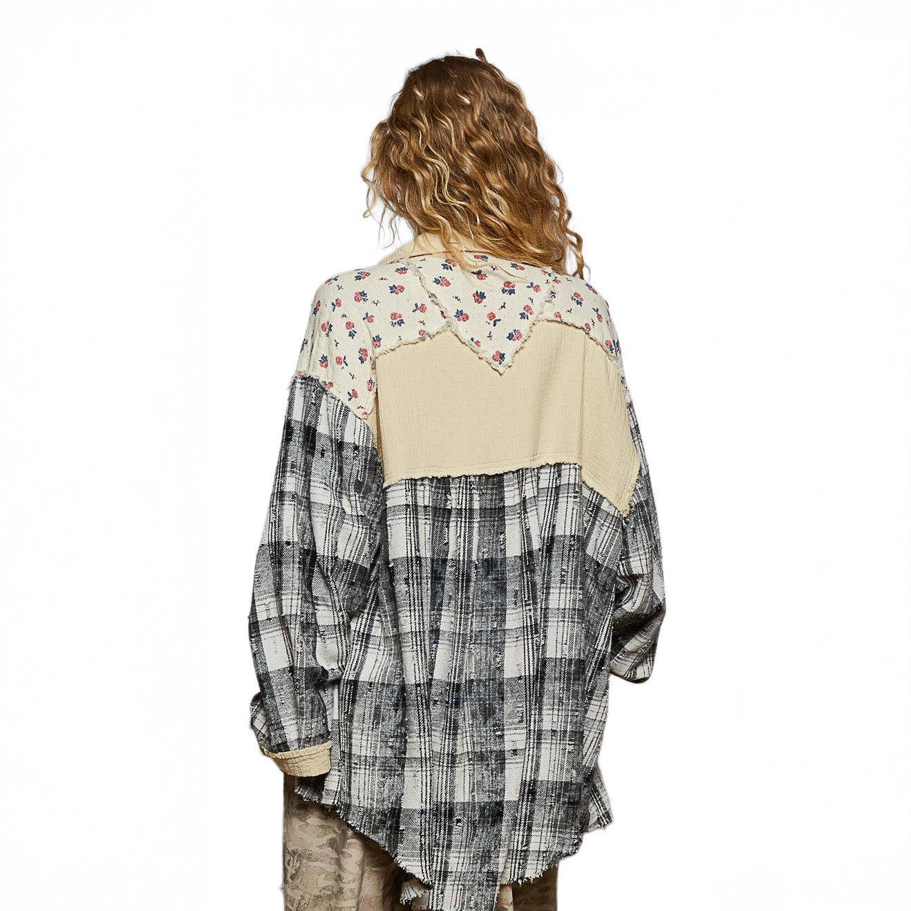 Person wearing a patchwork shirt with floral and plaid patterns on a plain background