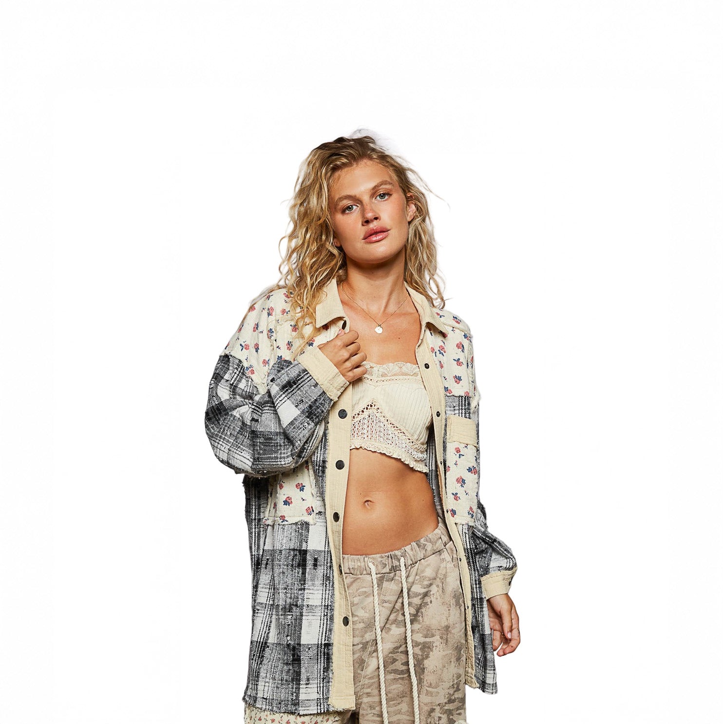Woman wearing a plaid shirt over a crop top and pants on a white background