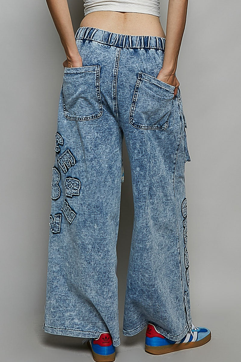 Person wearing blue acid-wash jeans with a gray background