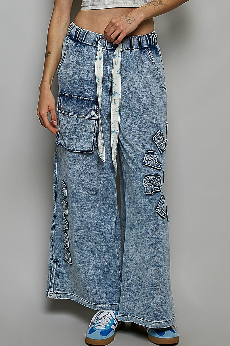 Person wearing wide-leg acid-wash jeans with a gray background