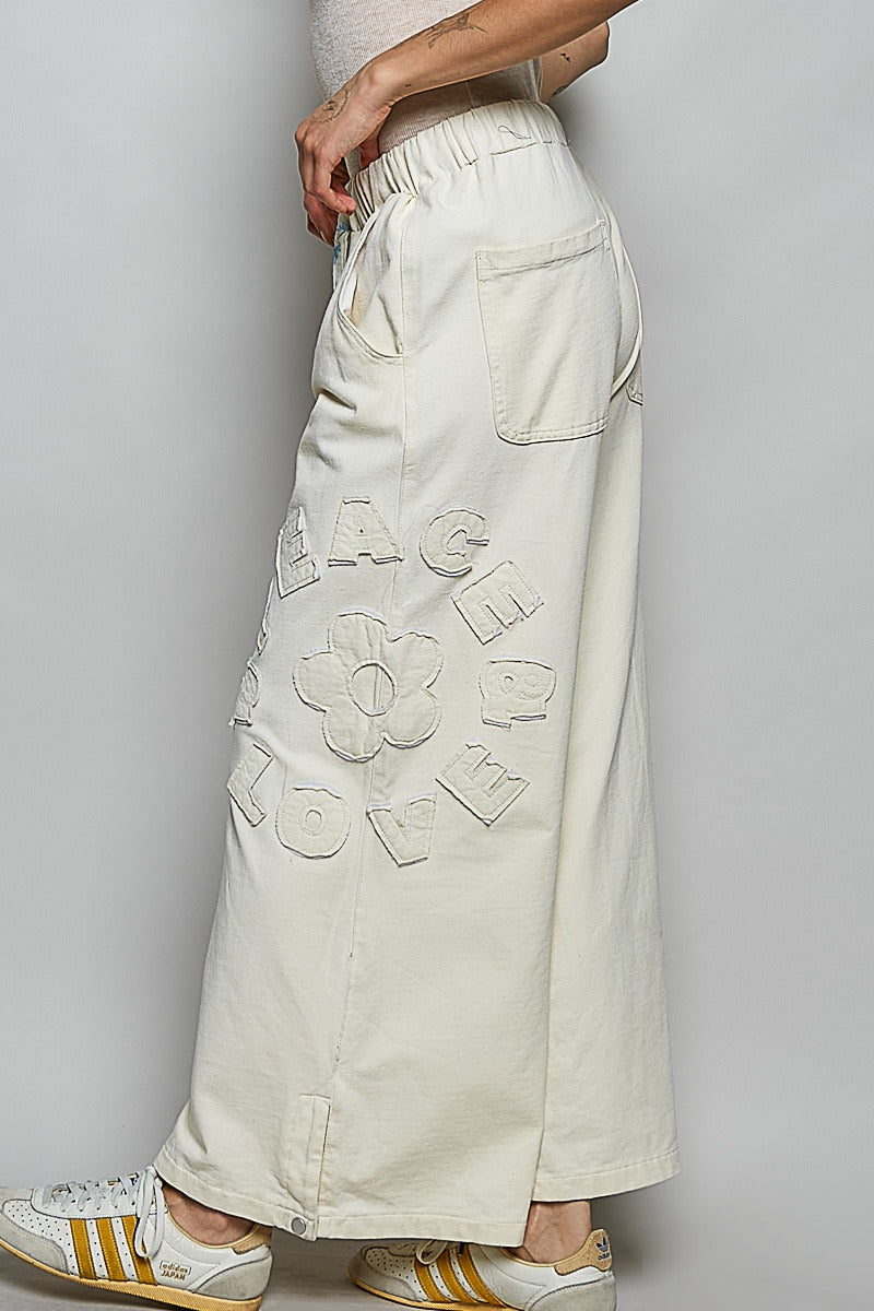 White pants with floral patterns worn by a person on a plain background