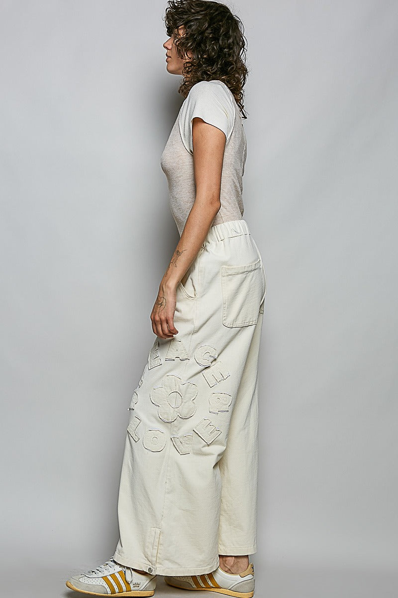 Woman wearing a light-colored top and wide-leg pants against a plain background