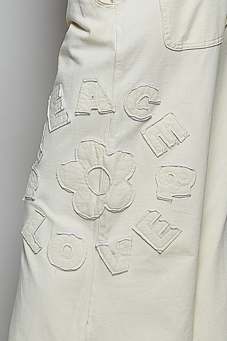 Close-up of a beige garment with embroidered letters and shapes.