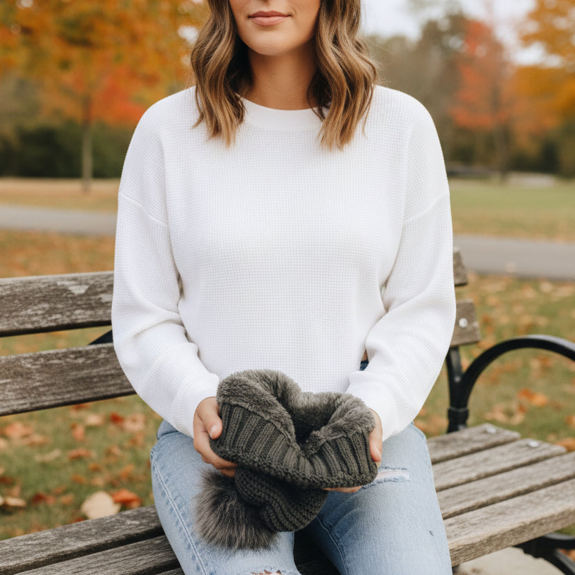 Person holding a dark gray knitted item with fluffy texture