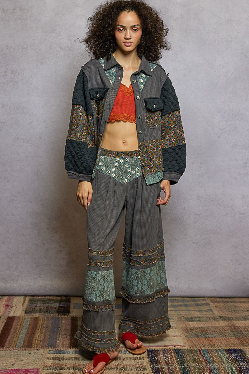 Woman wearing a patterned jacket and pants standing against a plain background