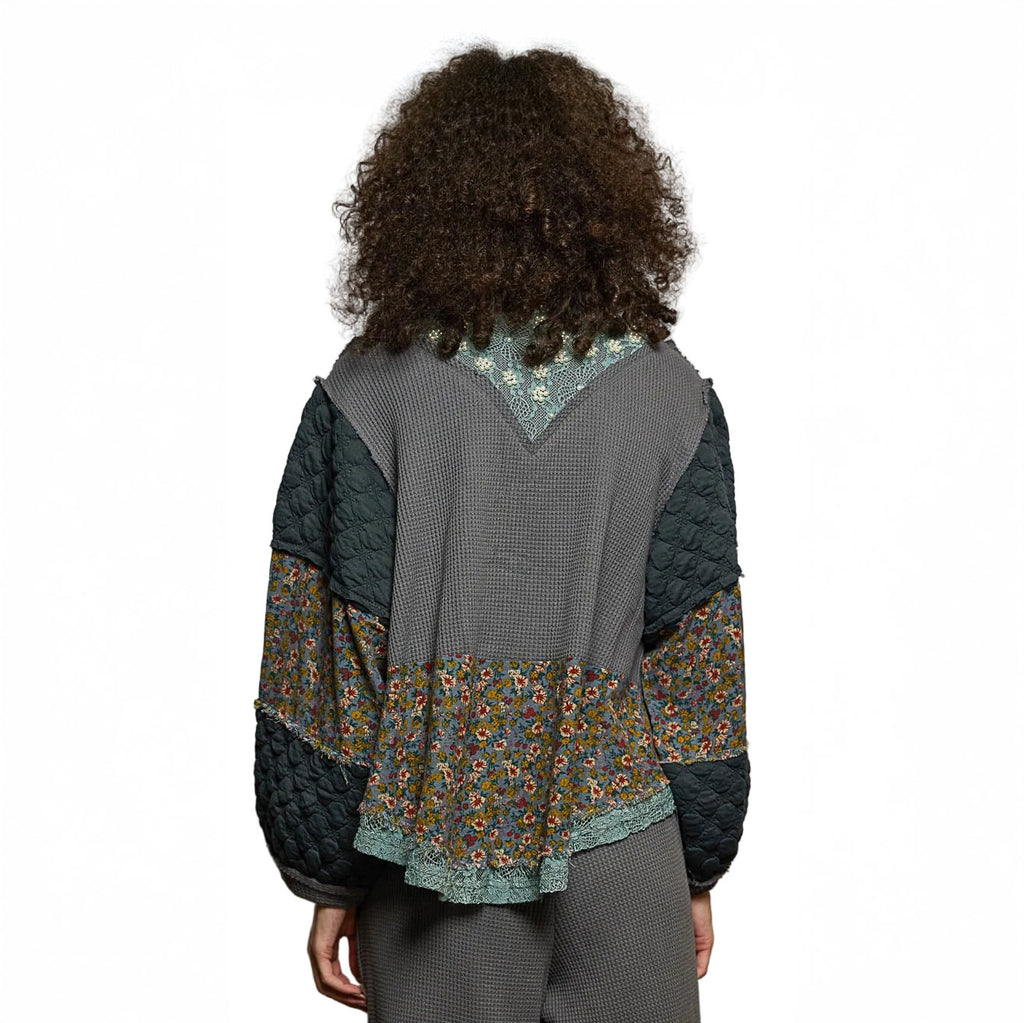 Person wearing a quilted jacket with floral patterns on a plain background