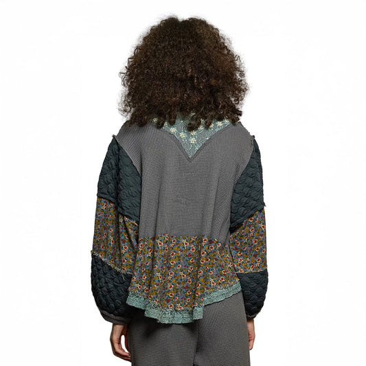 Person wearing a quilted jacket with floral patterns on a plain background