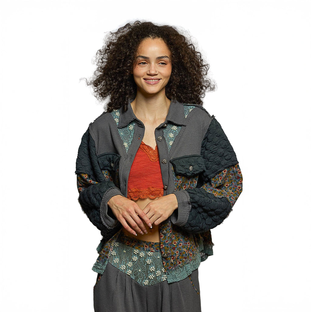 Woman wearing a layered outfit with a floral jacket and red top on a white background