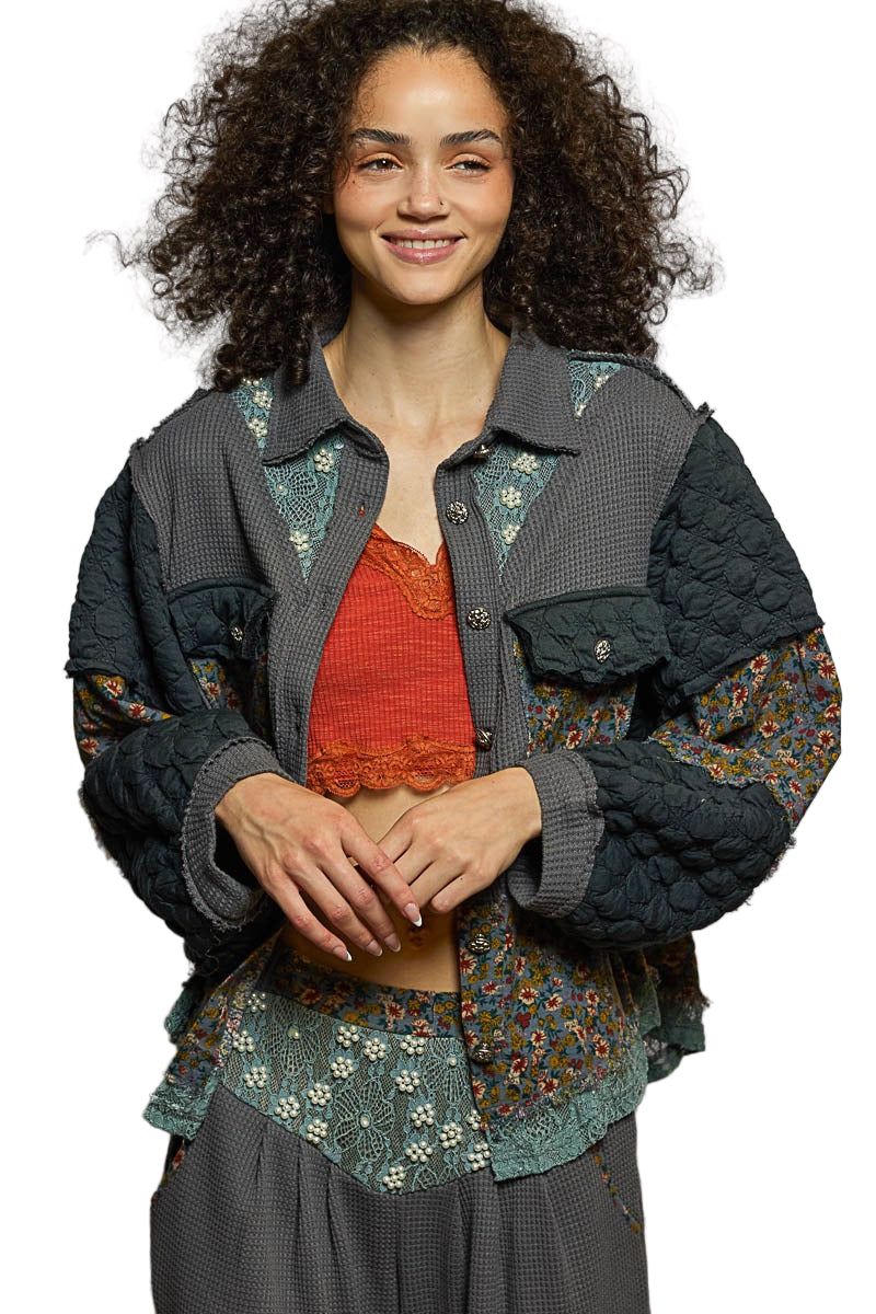 Woman wearing a layered outfit with a floral jacket and red top on a white background
