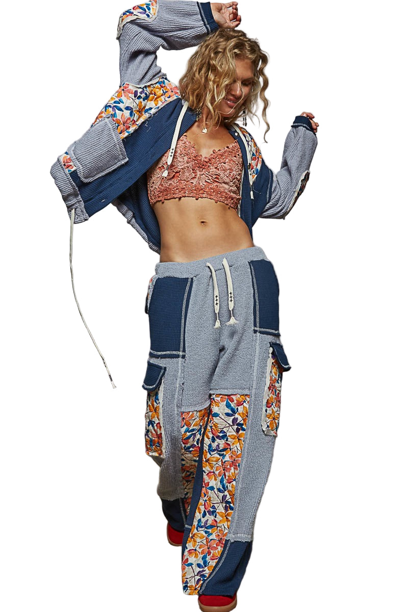 Woman wearing a colorful outfit with a floral pattern and gray jacket on a white background