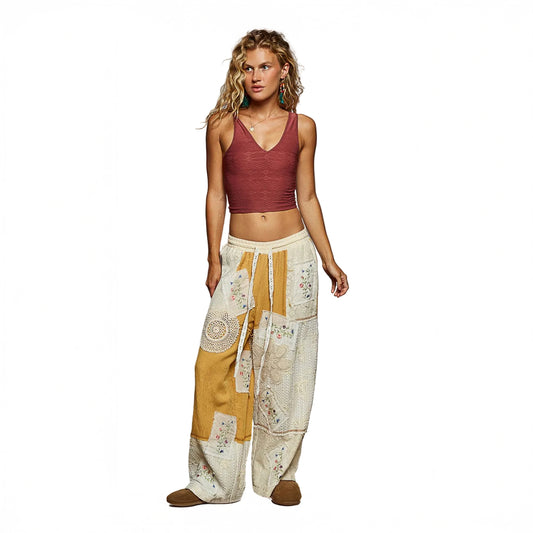 Woman wearing a burgundy crop top and patterned pants against a gray background